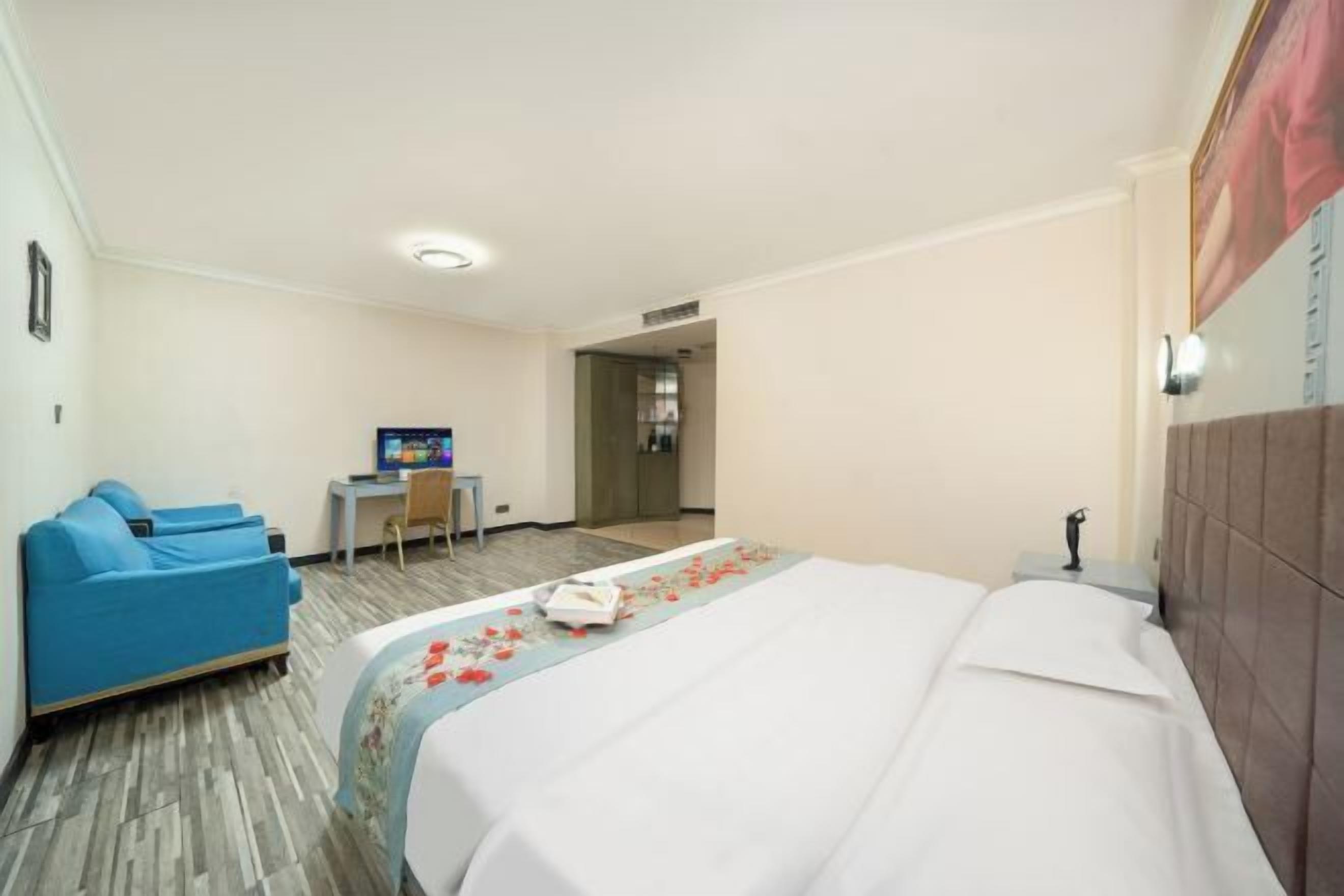 A hotel room with a bed, a blue sofa, a desk, and a television.