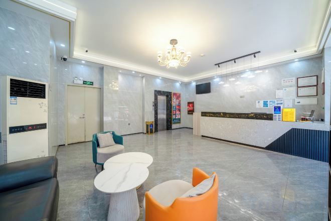 A hotel lobby with a reception desk, seating area, and a chandelier.