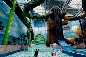 Een overdekt waterpark met glijbanen, een bällebad en een grote, gebogen ingang.