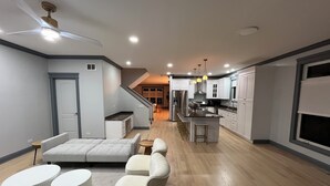 Una cuina moderna amb armaris blancs, una illa central i una zona de menjador amb tamborets.