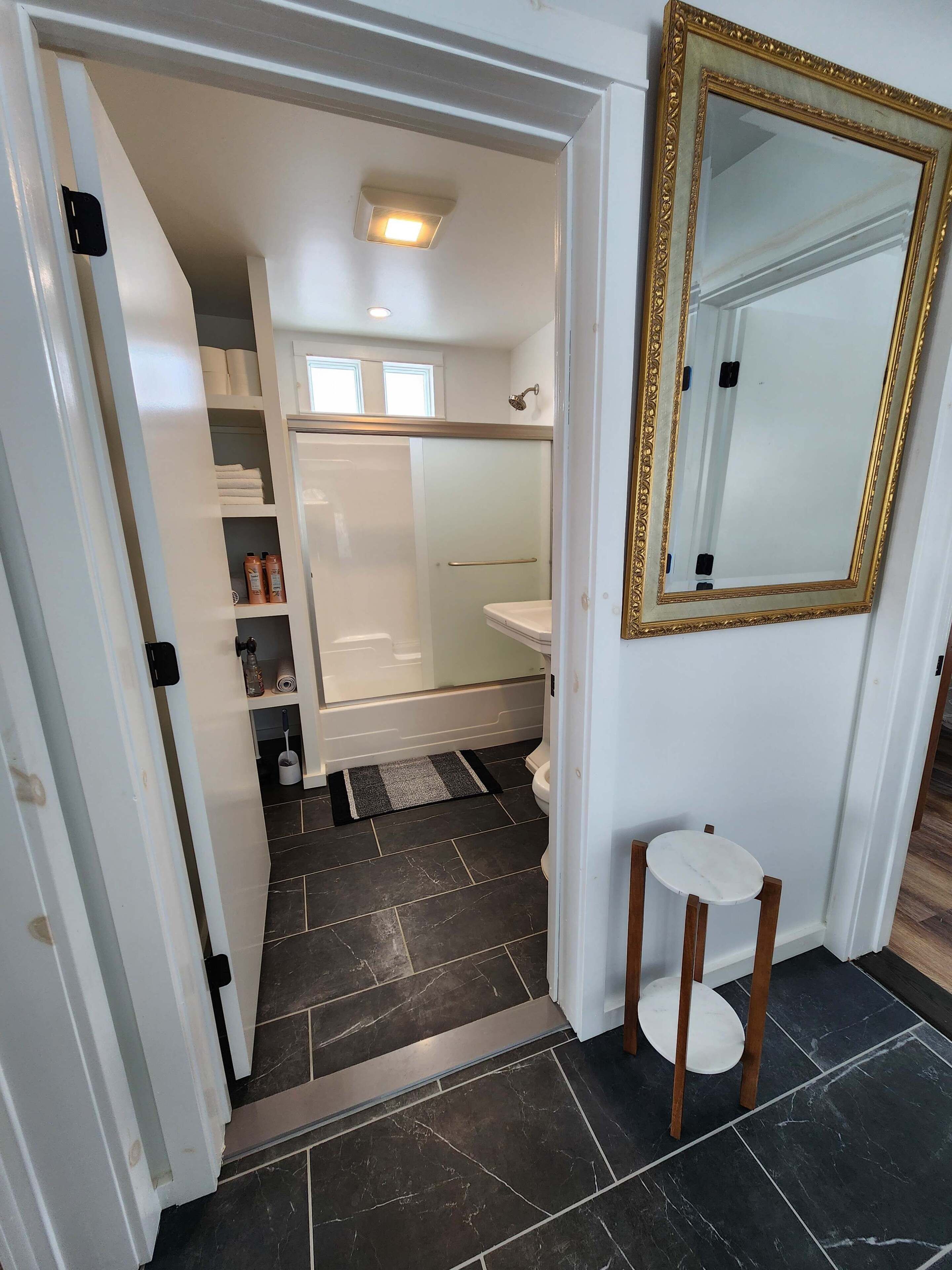 Une salle de bain avec une douche, des toilettes et une petite table.
