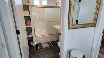 Une salle de bain avec une douche, des toilettes et une petite table.