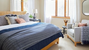 A bedroom with a large bed, bedside tables, a chair, and a window with curtains. - Cheerful Lutsen getaway 4bdrms and wifi (Lutsen)