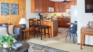 A modern kitchen with wooden cabinets, a central island with bar stools, a dining area with a table and chairs, and a living room with a sofa and a coffee table. - Cheerful Lutsen getaway 4bdrms and wifi (Lutsen)