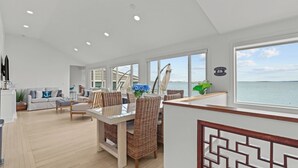 A spacious living area with a dining table, wicker chairs, a sofa, and a view of the sea. - Luxury seaside retreat (North Kingstown)