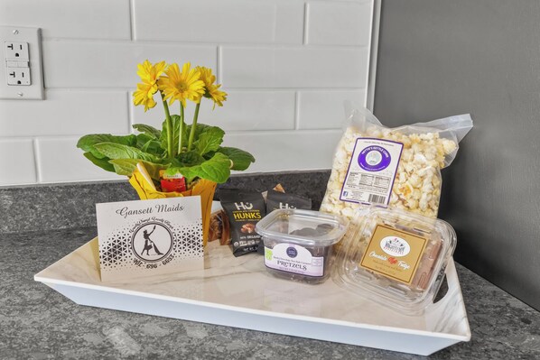 Een dienblad met snacks, waaronder popcorn, pretzels en chocolademousse, een visitekaartje en een bloem.