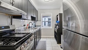A modern kitchen with stainless steel appliances, a gas stove, and a built-in oven. - Plainview Haven (Detroit)