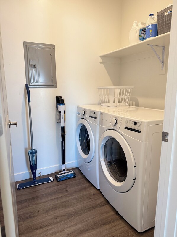 A laundry room with two front-loading washing machines, a mopping bucket, and a mop. - Brand New Condo in Spanish Fork (Spanish Fork)