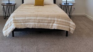 A bedroom with a bed, two bedside tables, a window, and a ceiling light. - Brand New Condo in Spanish Fork (Spanish Fork)