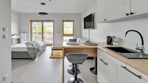 A modern, well-lit room with a bed, a dining area, and a kitchen.