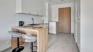 A modern kitchen with white cabinets, a wooden island with bar stools, and a wooden door in the background.