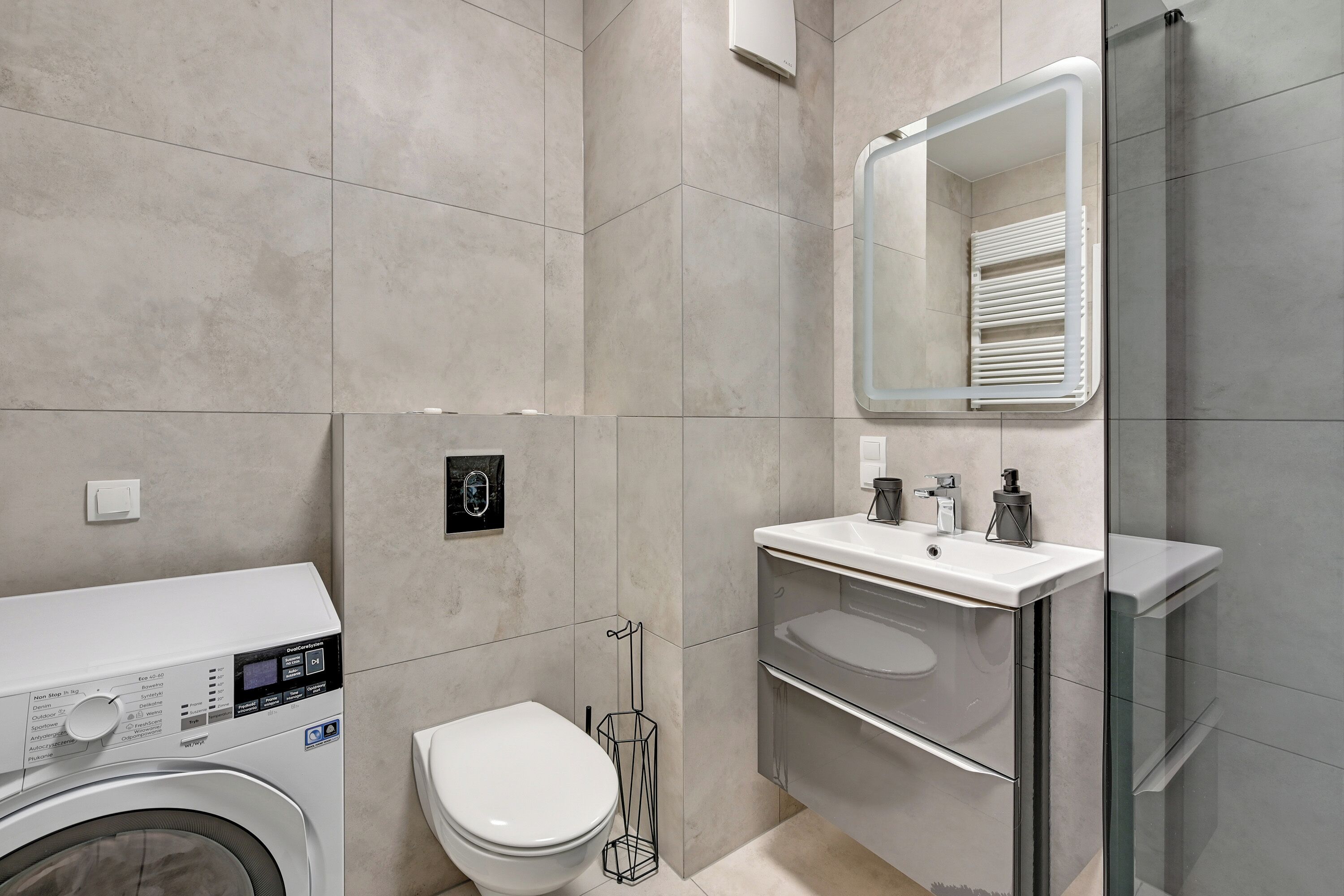 Ein modernes Badezimmer mit Waschmaschine, Toilette und Duschkabine.