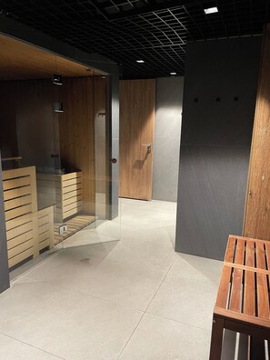 Un espacio de oficina moderno con separadores de vidrio, un banco de madera y piso de baldosas.