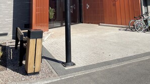 A modern building entrance with a wooden canopy, a bike parked outside, and a bench.