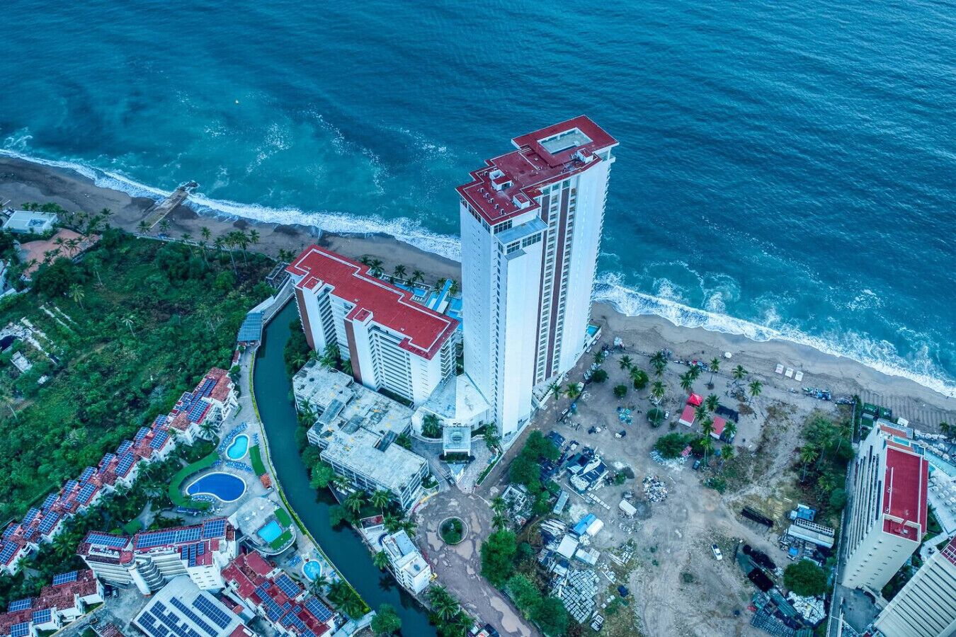 Vista aérea de un hotel costero con varias edificaciones, una playa y un río.