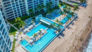 A resort with a large swimming pool, beach, and high-rise buildings. - Charming Oceanfront Condo (Puerto Vallarta)