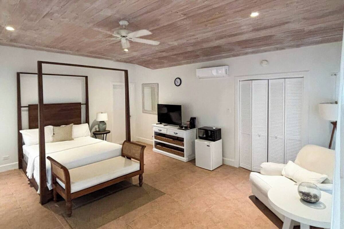 Ein Schlafzimmer mit einem Himmelbett, einem Fernseher, einer Mikrowelle, einem Sofa und einem Kleiderschrank.