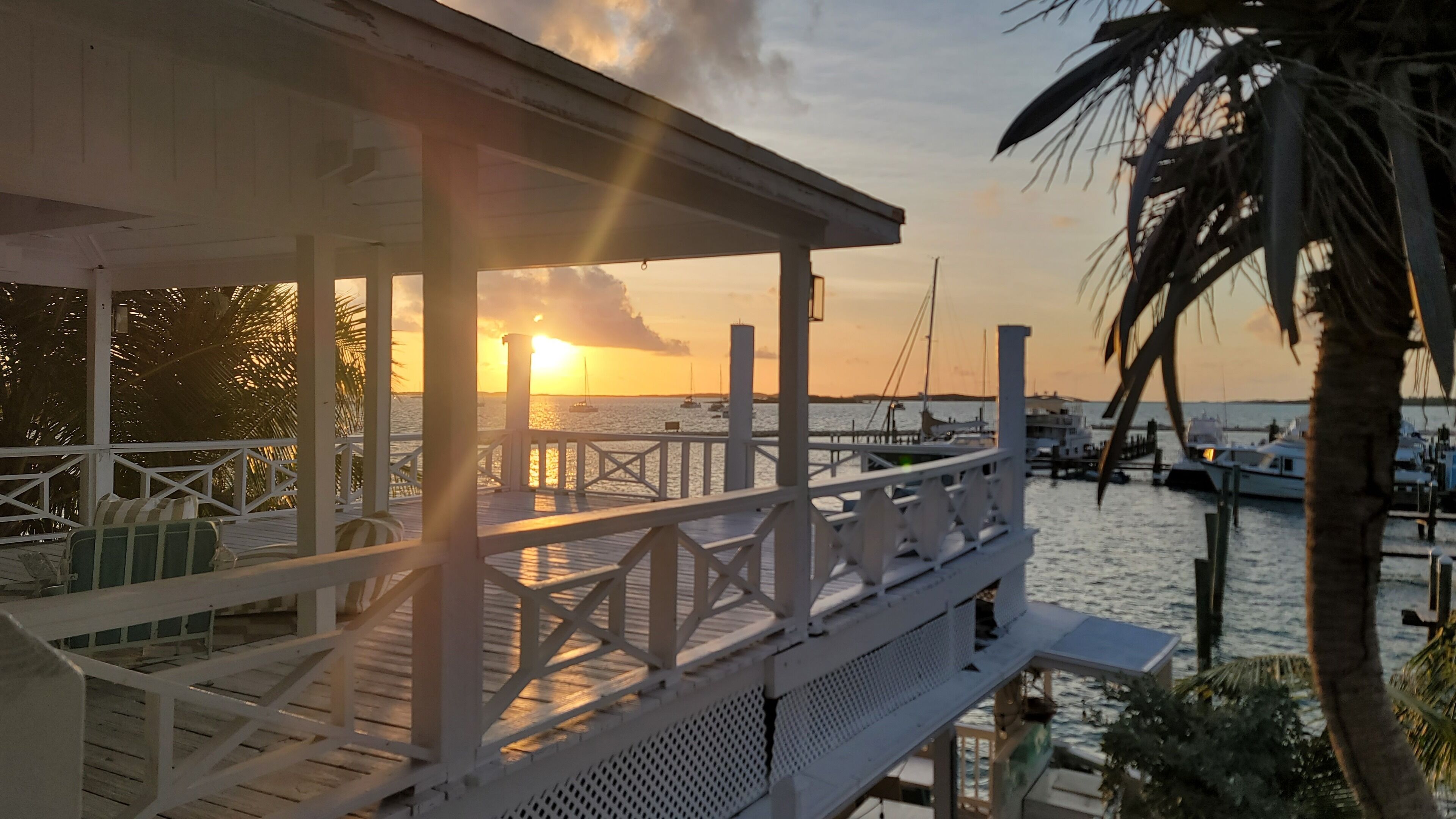 A wooden deck with railings overlooking a marina at sunset.