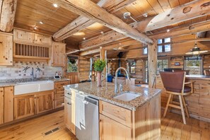 A wooden cabin-style kitchen with granite countertops, a dishwasher, and a bar area.