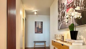 A hallway with a wooden floor, a bench, a desk with a plant, and a framed picture on the wall. - City Views & Comfort at Schaffhauserplatz (Zürich)