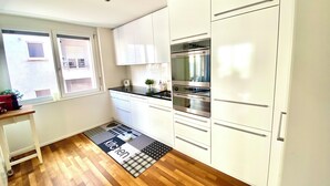 A modern kitchen with white cabinets, a black countertop, and a built-in oven. - City Views & Comfort at Schaffhauserplatz (Zürich)