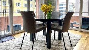 A modern dining area with a glass table, four chairs, and a vase of yellow flowers. - City Views & Comfort at Schaffhauserplatz (Zürich)