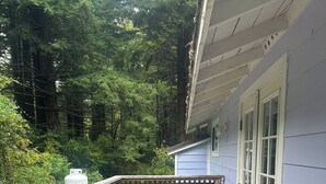 A wooden deck with a table and chairs, surrounded by a wooden fence and lush greenery. - Cozy cottage in charming Trinidad with WiFi (Trinidad)