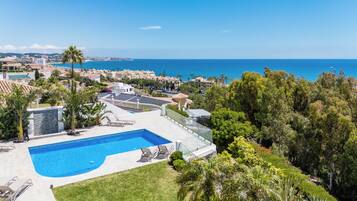 Un resort con piscina, sillones de descanso y vista al océano.
