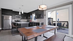 A modern kitchen with dark cabinetry, stainless steel appliances, and a central island with seating.