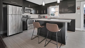 A modern kitchen with dark cabinets, stainless steel appliances, and a central island with bar stools.