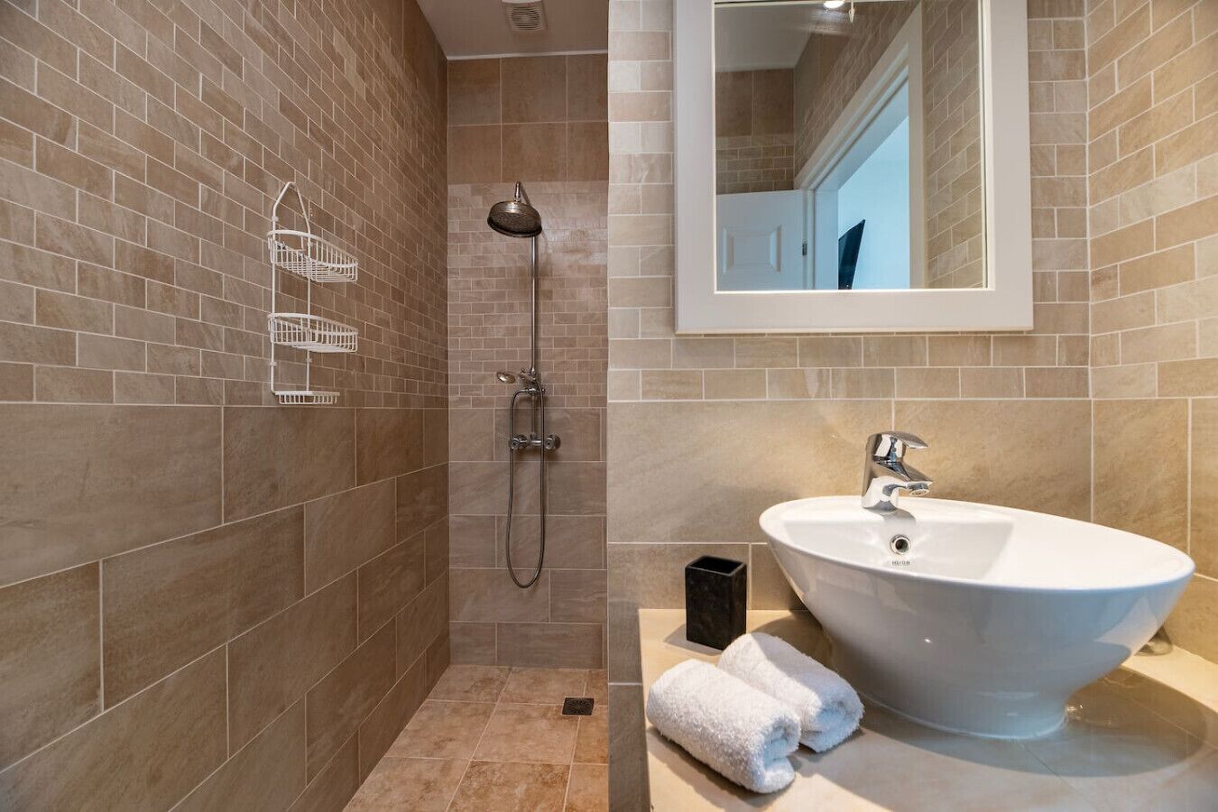 A bathroom with a shower, a sink, and a mirror.