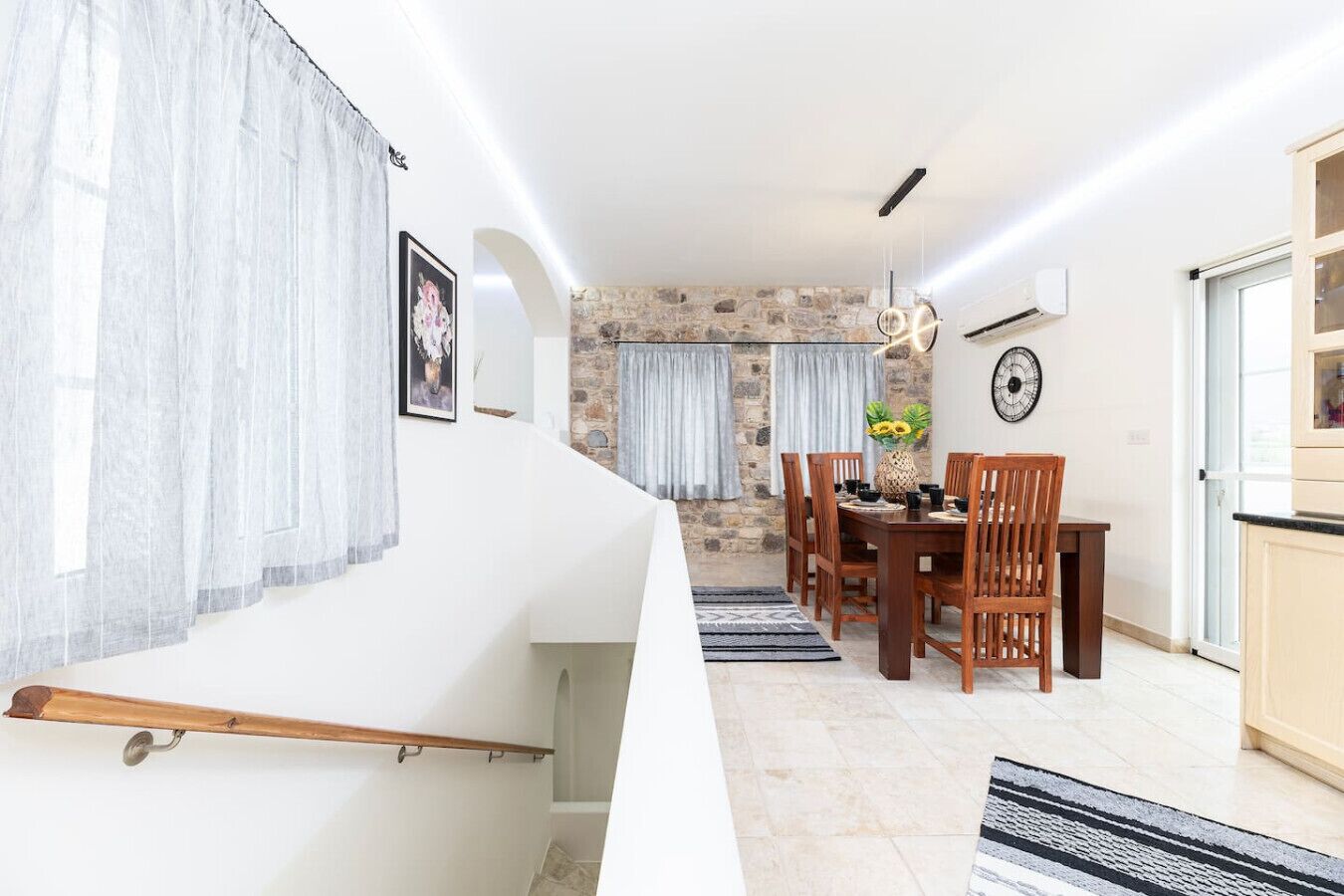 Un espace repas moderne avec un mur en pierre, une table à manger en bois et des chaises.