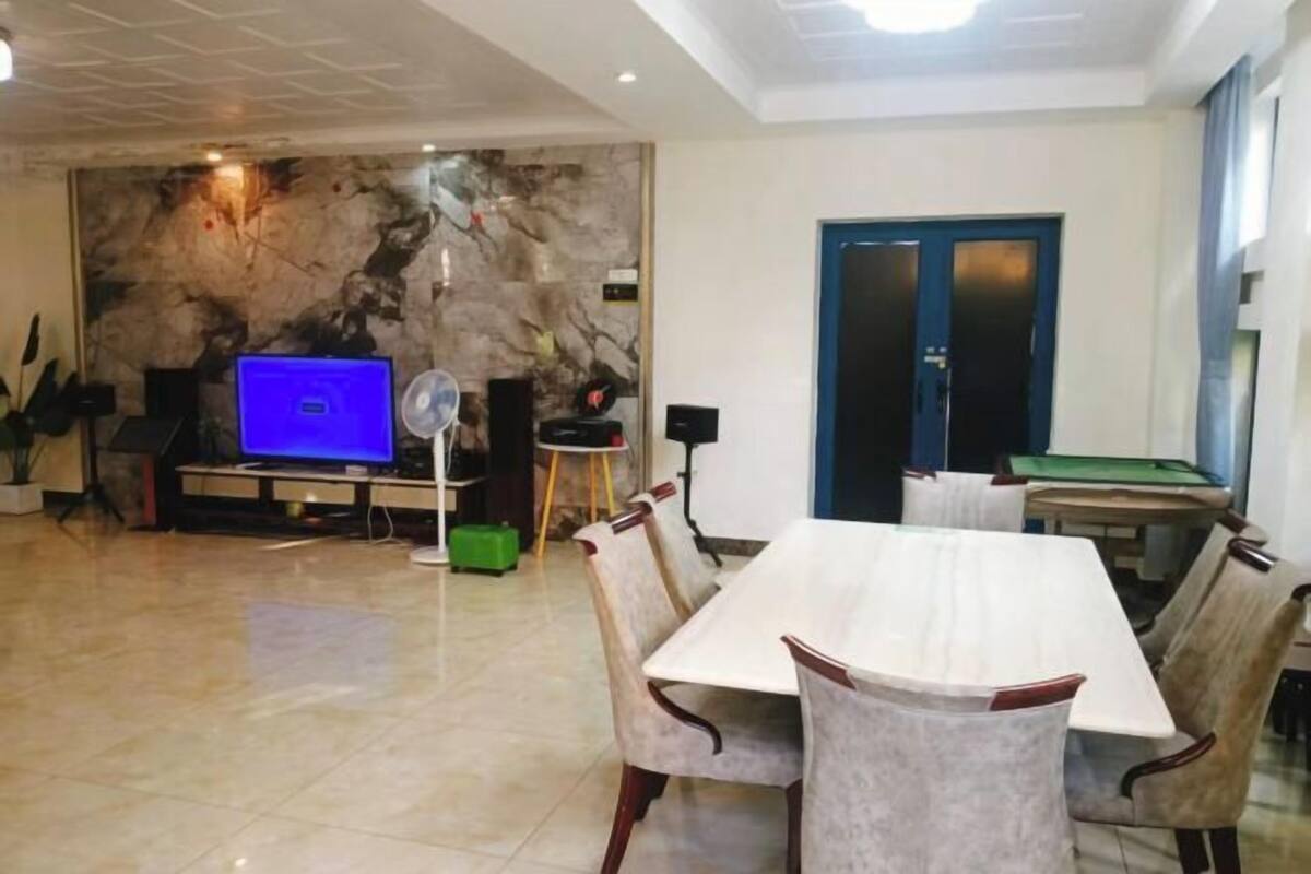 A modern dining area with a marble wall, a television, and a pool table.