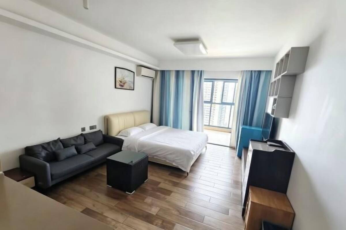 A modern hotel room with a bed, sofa, and a desk.