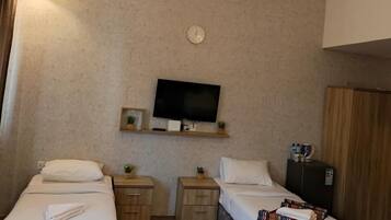 Habitación de hotel con dos camas, televisión, reloj y armario.