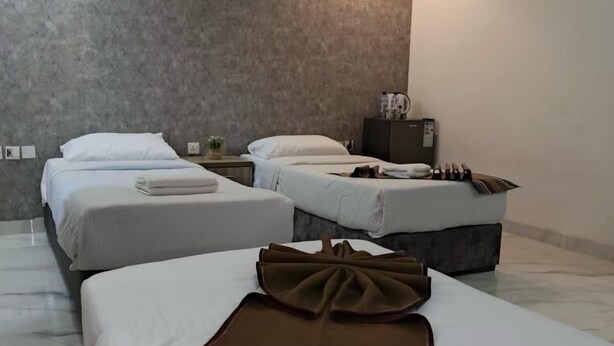 A hotel room with three beds, a marble floor, a grey textured wall, and a hanging light fixture. - Gate inn hotel (Amman)