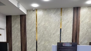 A reception area with a marble wall, a wooden reception desk, and a tiled floor. - Gate inn hotel (Amman)