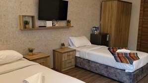 A hotel room with two beds, a TV, a wardrobe, and a clock on the wall. - Gate inn hotel (Amman)