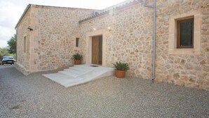 A stone building with a gravel driveway, two potted plants, and a car parked outside.
