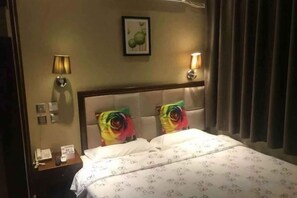 Ett hotellrum med en säng, två vägglampor, ett nattduksbord och en inramad tavla på väggen.