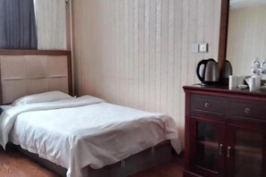 A hotel room with a bed, a wooden headboard, a dark wooden dresser with a mirror, and a kettle on the dresser. - Super 8 Hotel (Beijing Fengbo Metro Station) (Beijing)