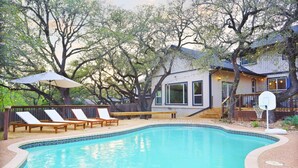 A swimming pool with lounge chairs and a wooden deck. - Ultimate Retreat 5-bed, Pool, Hot Tub, Mini Golf, Game Room, Playground and More (San Antonio)