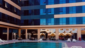 A hotel with a swimming pool, outdoor seating, and a modern building facade. - MODERN APARTMENT (Istanbul)