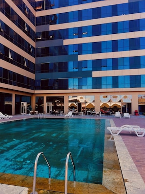 Un hotel amb piscina, zones d'estar a l'exterior i una façana d'edifici moderna.