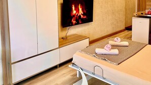 Un dormitorio moderno con televisor, armario de madera y cama con toallas.