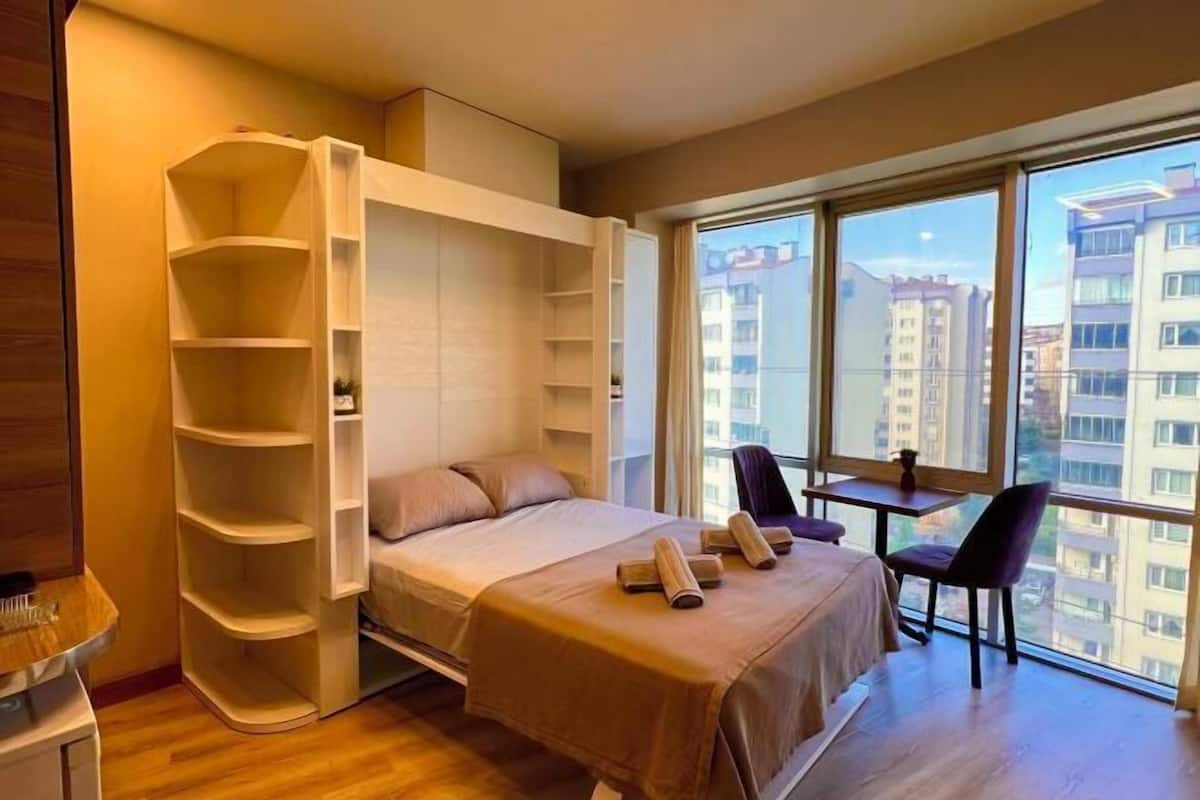 A bedroom with a bed, built-in shelving, a small table, and chairs.