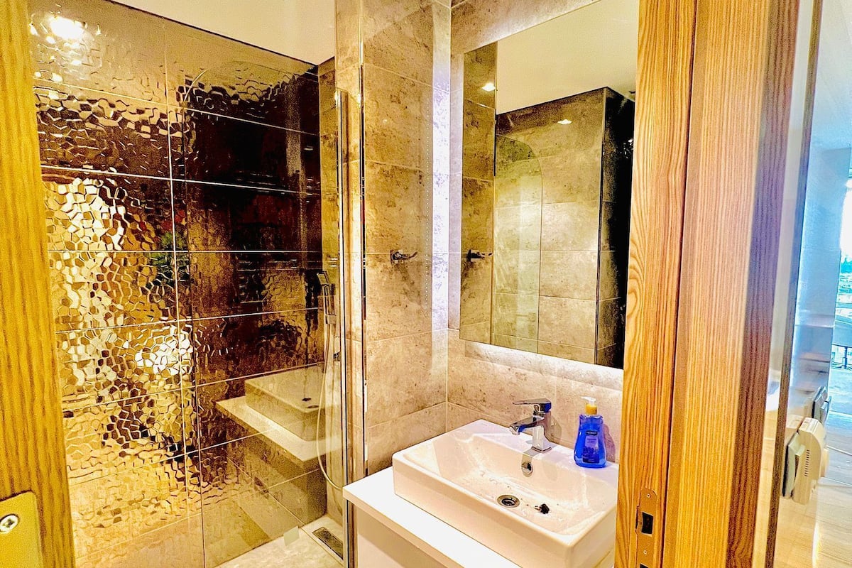 A modern bathroom with a glass shower enclosure, a white sink, and a wooden vanity.