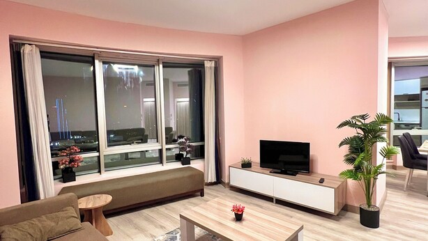 Una sala de estar moderna con un sofá, una mesa de centro, un televisor y un ventanal con vistas.
