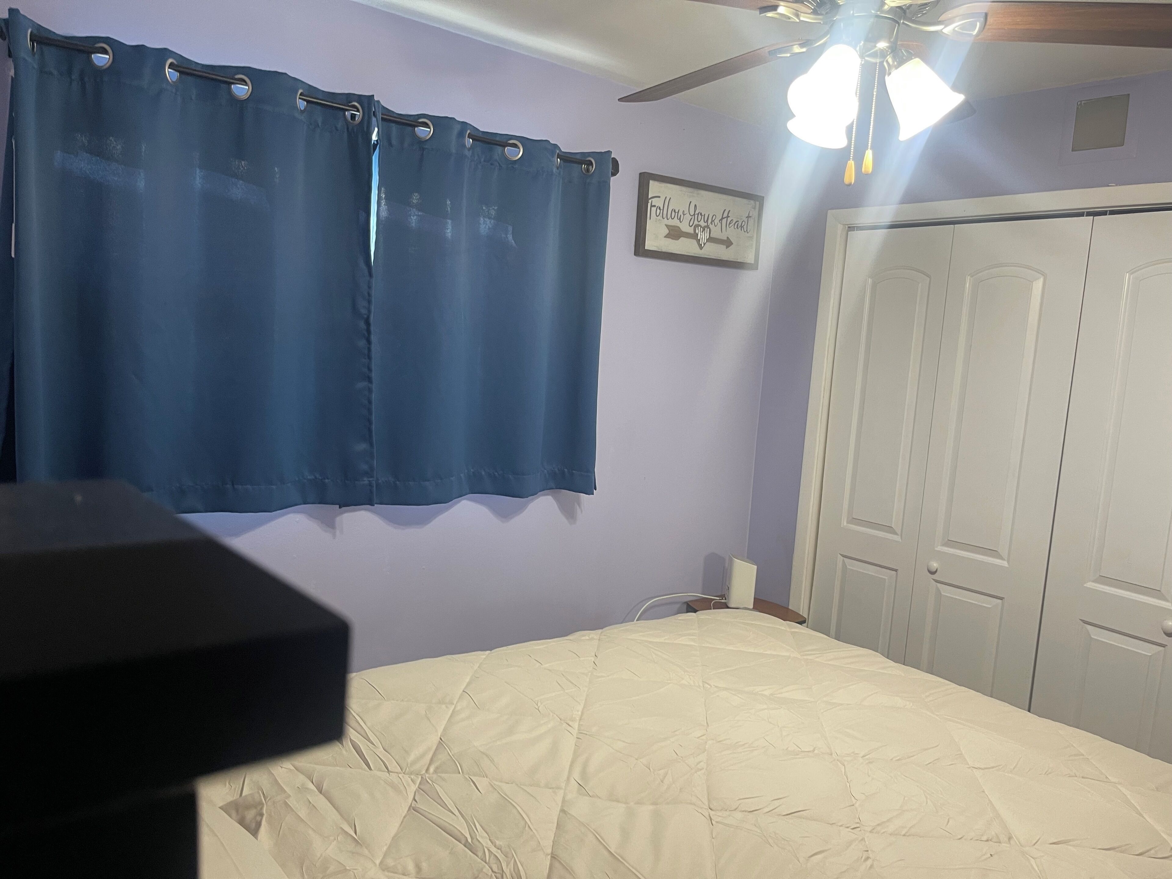 Un dormitorio con cama, ventilador de techo y armario.