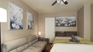 Un dormitorio con una cama, un sofá y dos cuadros colgados en la pared.